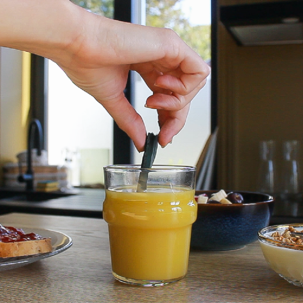 Feuille de spiruline surgelée trempée dans un verre de jus d'orange pour un petit déjeuner énergétique